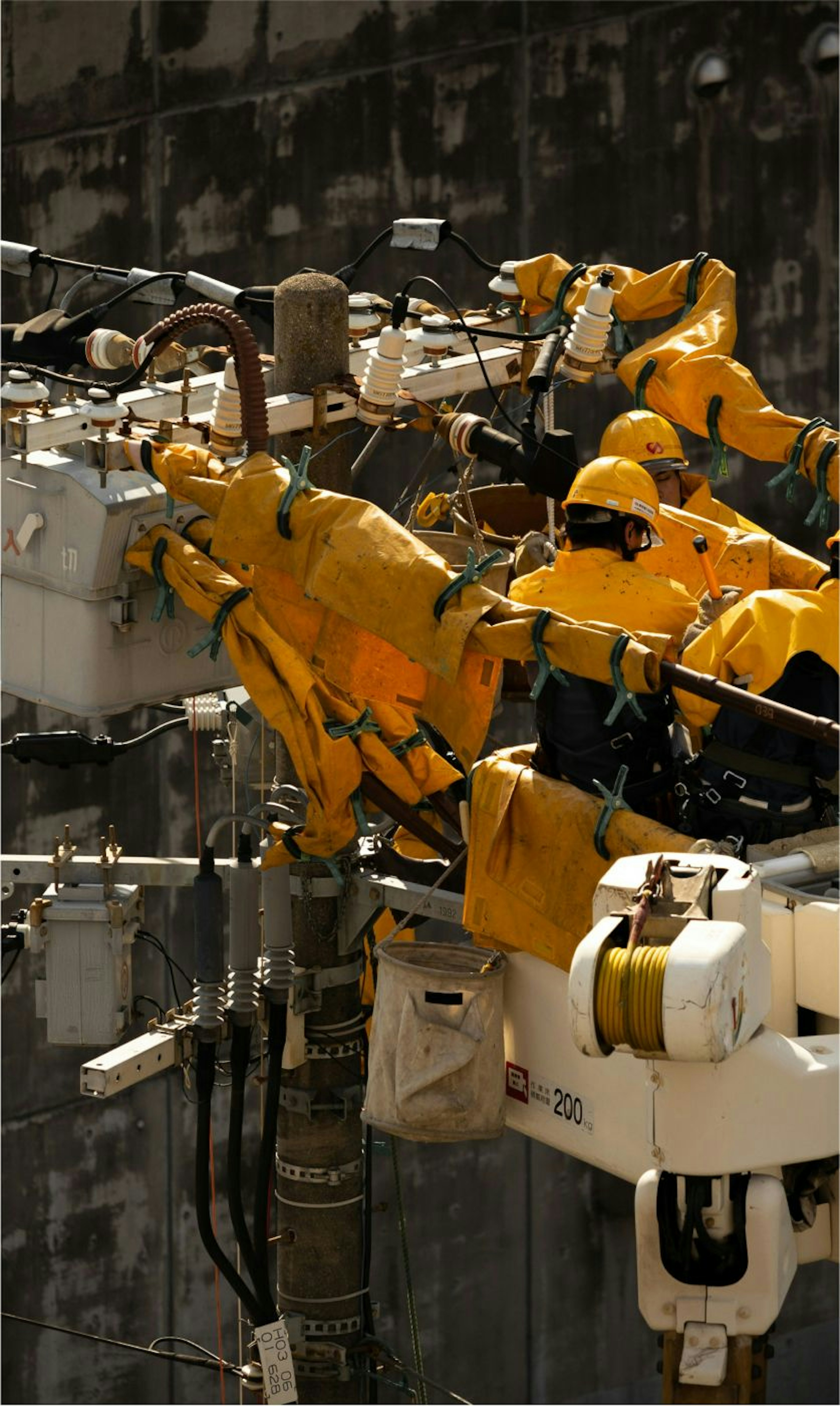 Workers dressed in yellow suit fixing an electricity tower